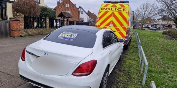 A seized white car and police van in a residential street