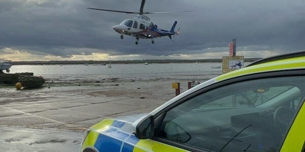 Coast guard landing helicopter in West Mersea with police car in the foreground