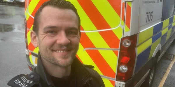 Sergeant Jamie Challis taking a selfie in front of a police vehicle