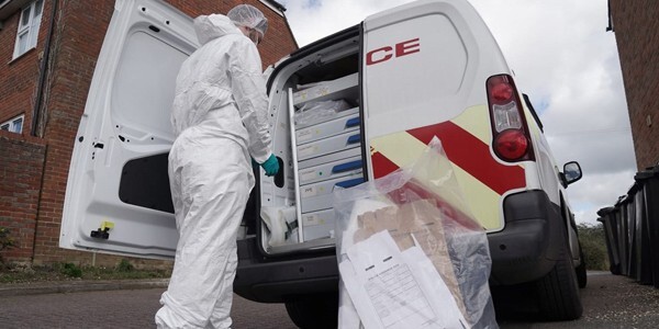 Scenes of crime officers dressed in white protective overalls with evidence bag at the back of a police van near Orchard Way, Thaxted