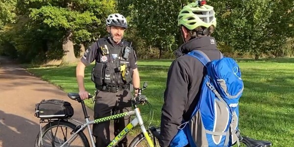 Sergeant Ben Felton speaks with a cyclist in a country park