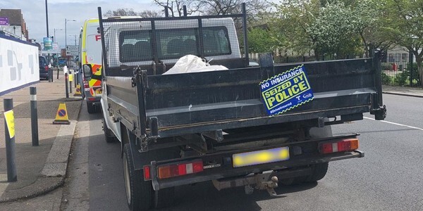 Black open-backed truck with a 'seized by police' sticker on it