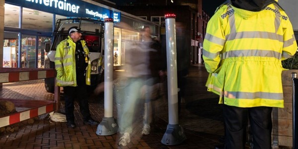 Two police officers at night supervising the use of a knife arch in a town centre