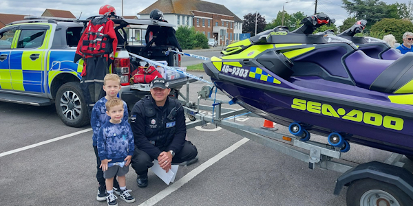 Two children standing next to officer from Marine unit. 