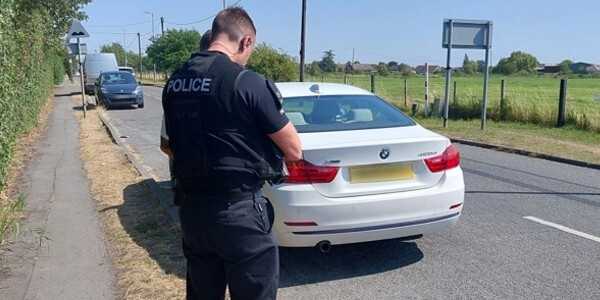 Officer talking to a driver next to their white car at the side of the road