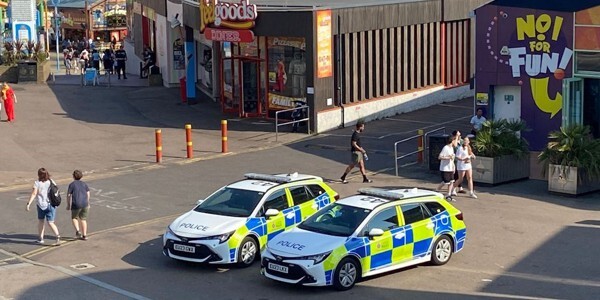 Two police cars parked in front of seafront businesses