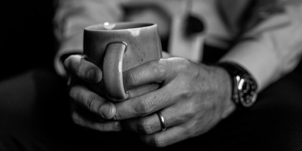 Black and white photo of male hands holding a mug