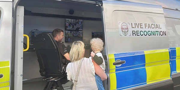 Adult and child speaking to officer operating live facial recognition system