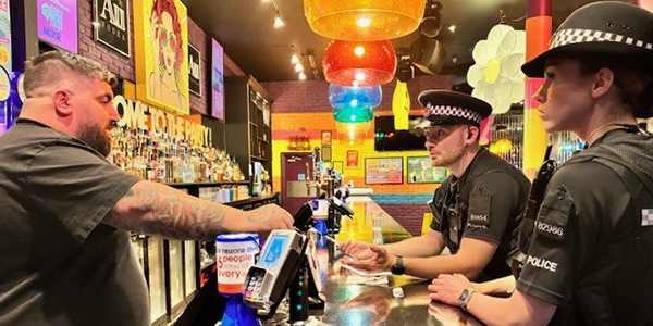 Uniformed police officers speaking to bar staff 