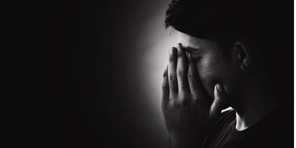 Black and white - woman with head in hands in a spotlight