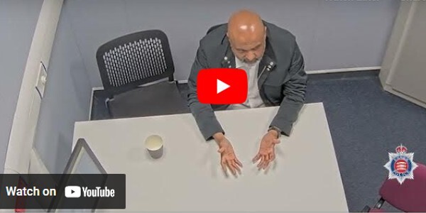 Video - man in an interview suite being questioned by police officers