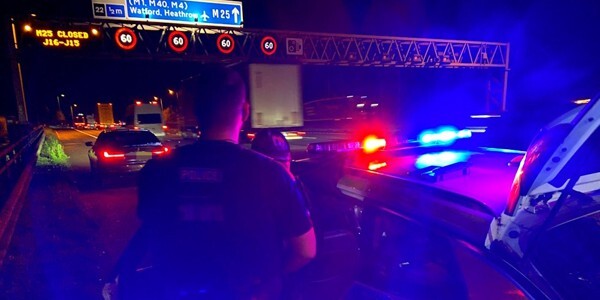 Officers and police cars at night on a major road network