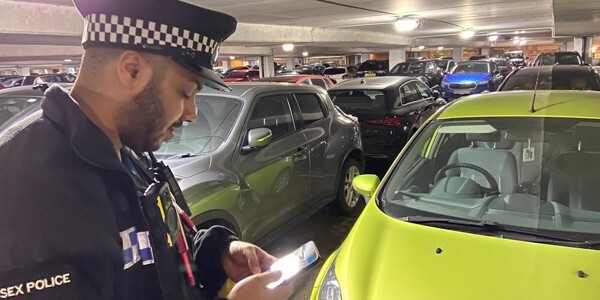 Officer checking vehicle details in a car park