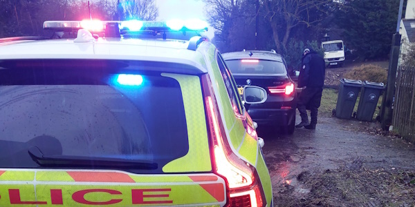 Police vehicle parked behind a black vehicle - A police officer is speaking to the driver of the black vehicle through the window