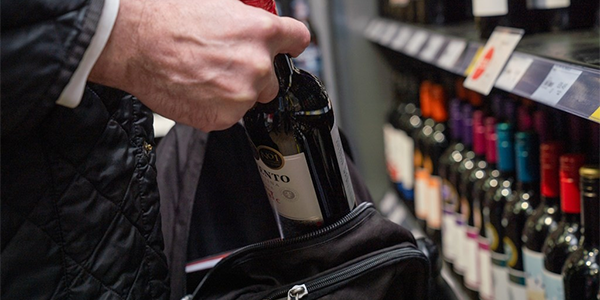 Person putting bottle of red wine into their backpack