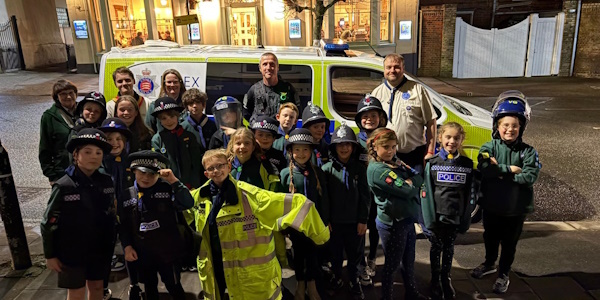 PC McNamara standing with the cubs in front of a police vehicle 