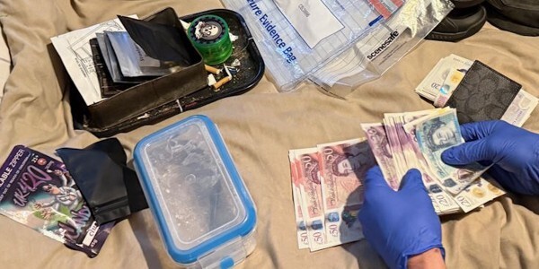 police officer wearing gloves counting money from drugs haul