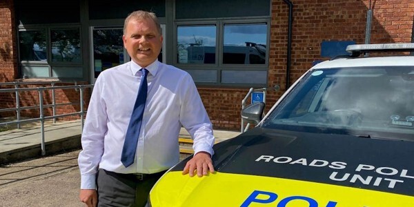 Adam Pipe - Head of Roads Policing at Essex Police standing next to a patrol car