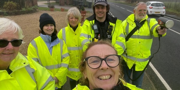 Six Community Speed Watch volunteers at the roadside in yellow reflective coats
