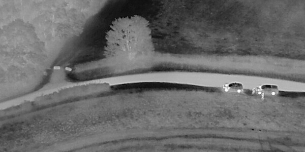 Black and white image from an infra-red drone video showing areal view of a field