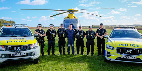 Rural Engagement Team officers standing in front of police helicopter and next to marked police cars