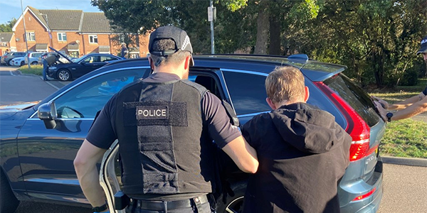 Officer leading arrested suspect to car