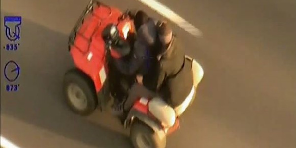 Helicopter view of two men riding a quadbike 