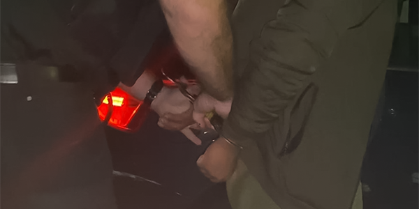 Person in handcuffs as they are arrested by police officer