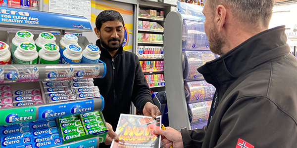 Business Crime Team officer handing flyer to shop staff