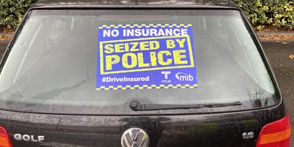 Drive Insured sticker on the rear windscreen of a black car