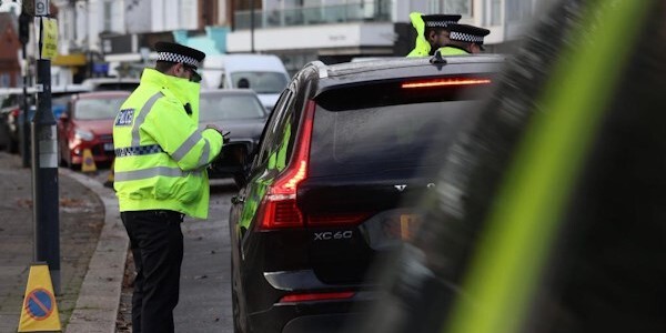 Police officer next to a parked car dealing with an incident