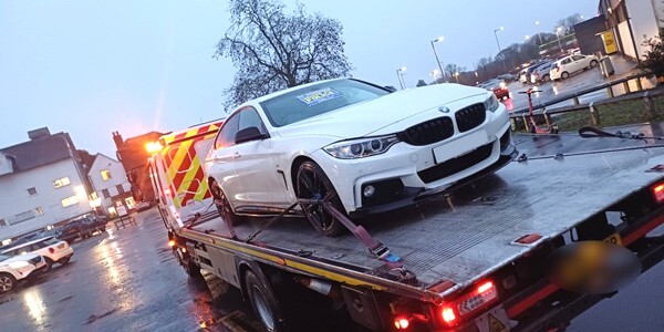 White BMW car on the back of a transporter lorry