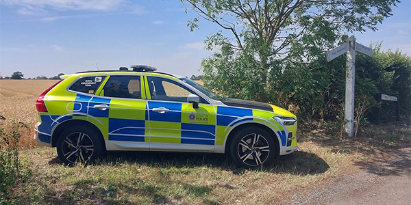 marked police car next to farmers field 
