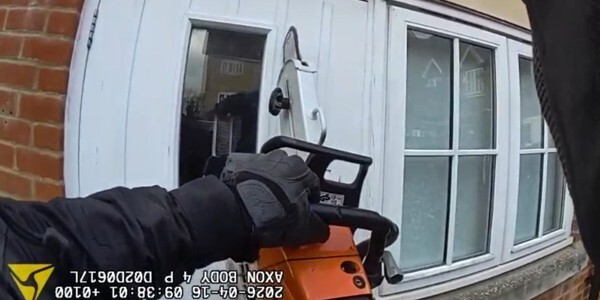 Body worn video image of an officer using a power saw to cut an access through a front door