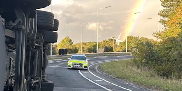 HGV on it's side on the road with police car in distance.