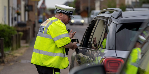 Police officer speaking to someone in a parked car 