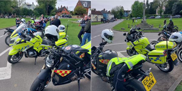 Police motorcycles and bikes parked at a community event, with officers speaking to members of the public in a village setting.
