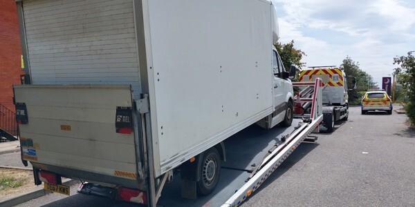 Large white van on a transporter lorry