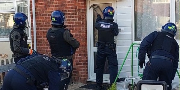 Police officers breaking a door to enter property to undertake drug raid