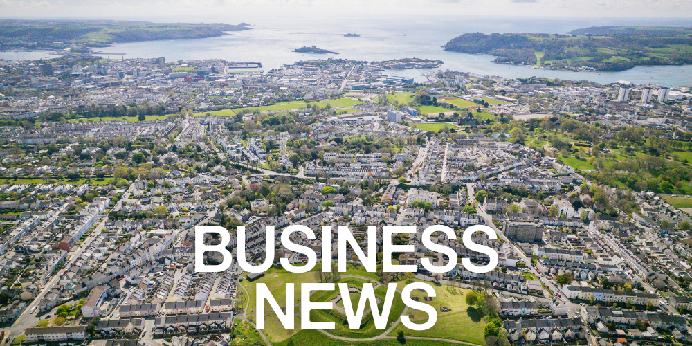 The image shows an aerial view of a city with neighborhoods, greenery, and water in the distance. 