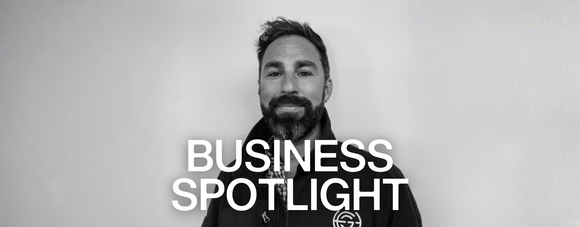 Black and white banner image with a person in a jacket centered and the words “BUSINESS SPOTLIGHT” in large white text across the bottom.