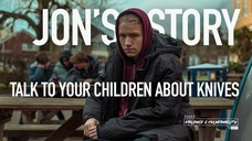 A boy sitting on a bench with a hoodie on 