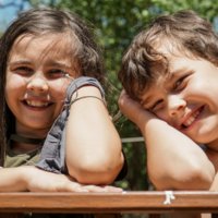 Young boy and girl laying on their tummys and smiling into the camera