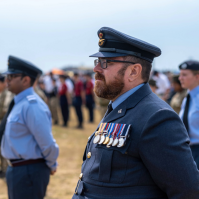 Man in navy uniform standing to attention at a parade