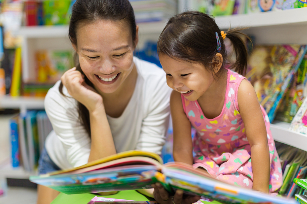 Mum & young toddler smiling reading books
