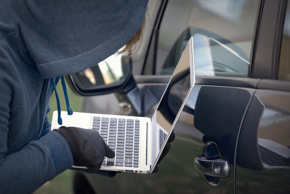 Hooded thief tries to break the car's security systems with laptop