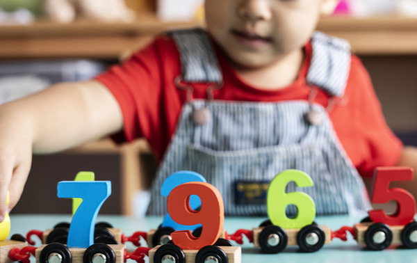 Little boy playing mathematics wooden toy at nursery