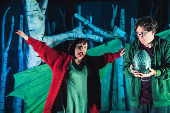 Man and woman on stage looking at large green egg