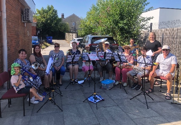 Members of the band with their instruments sit in the sun