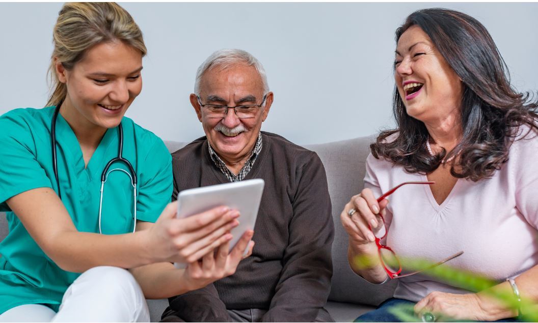 Medical staff looking at phone with man and woman, laughing.